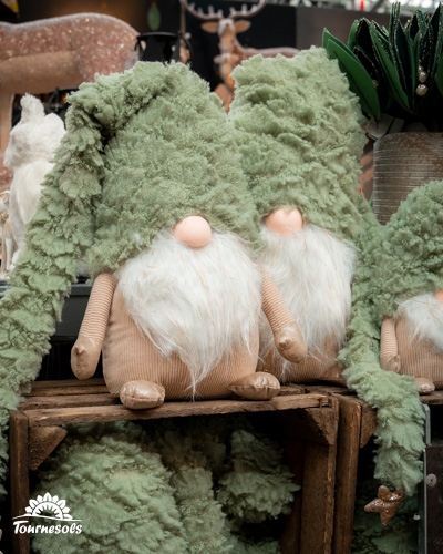 Poupées de Noël en laine verte exposées sur une étagère en bois.